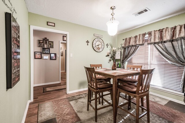 dining room with dark wood-type flooring and a textured ceiling