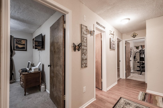 corridor with light hardwood / wood-style floors and a textured ceiling