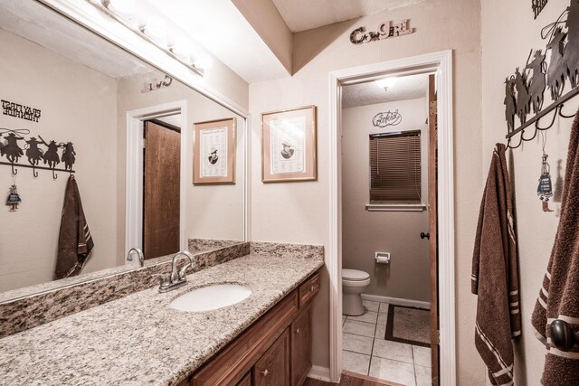 bathroom featuring vanity, tile patterned floors, and toilet