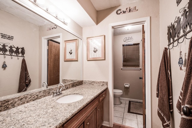 bathroom with baseboards, vanity, toilet, and tile patterned floors