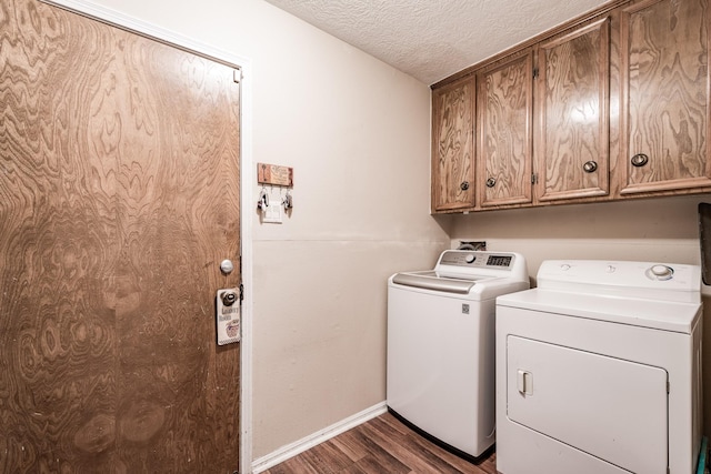 washroom with dark wood-type flooring, cabinets, washer and clothes dryer, and a textured ceiling