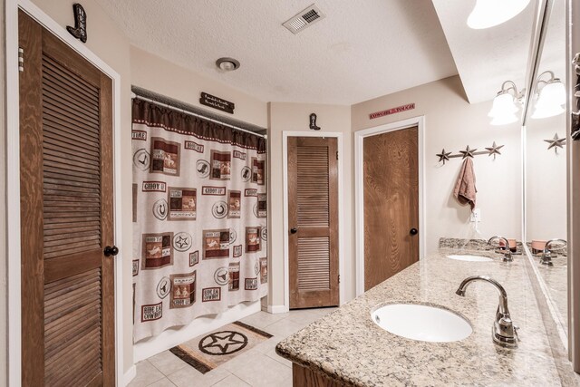 bathroom featuring tile patterned flooring, vanity, a textured ceiling, and a shower with shower curtain