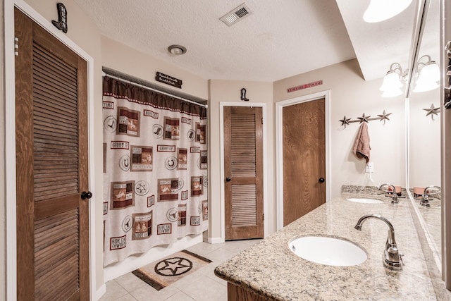 full bath with visible vents, a sink, a textured ceiling, and tile patterned floors