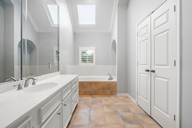 bathroom featuring tile patterned floors, crown molding, a skylight, vanity, and a relaxing tiled tub