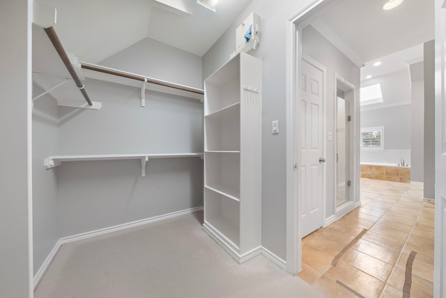 spacious closet featuring light tile patterned flooring and lofted ceiling