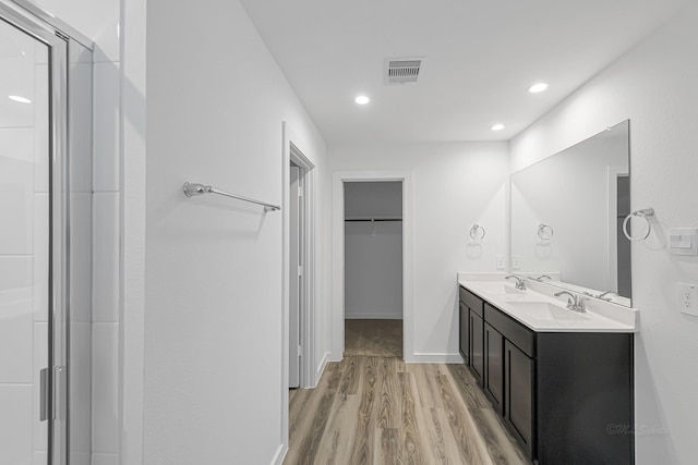 bathroom with wood-type flooring, vanity, and walk in shower