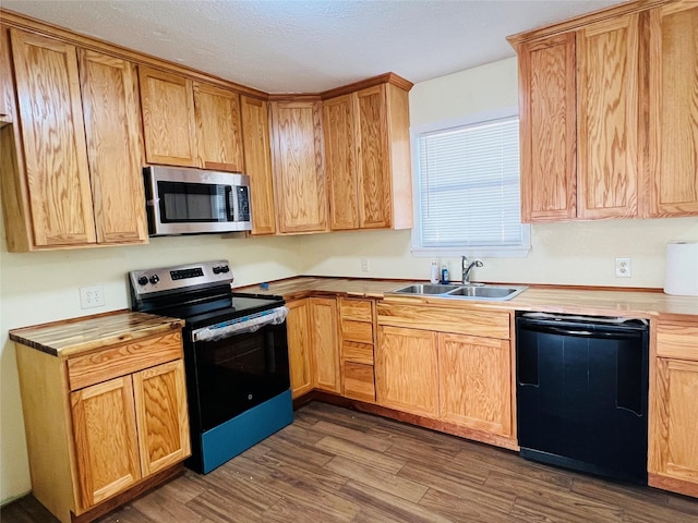 kitchen with sink, dark wood-type flooring, stainless steel appliances, and a textured ceiling