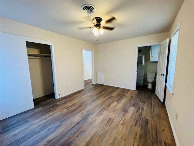 unfurnished bedroom with dark wood-type flooring, ceiling fan, ensuite bathroom, and a closet