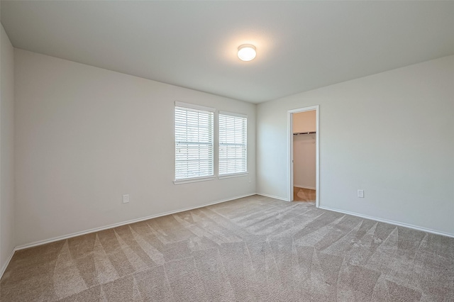 unfurnished bedroom featuring light carpet, a walk in closet, and a closet