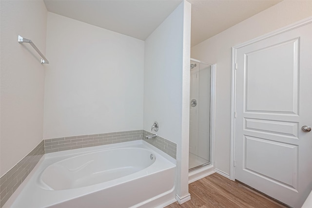 full bath featuring a shower stall, a garden tub, and wood finished floors