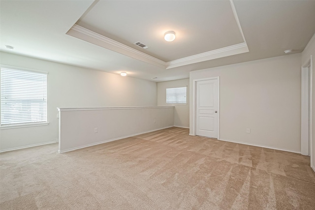 spare room with a raised ceiling, crown molding, light colored carpet, and visible vents