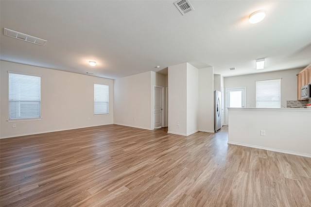 unfurnished living room with light wood-style floors, visible vents, and baseboards