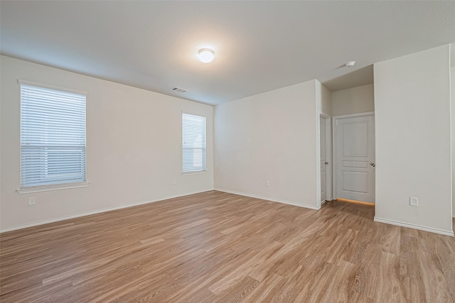 spare room featuring light wood-style flooring, visible vents, and baseboards