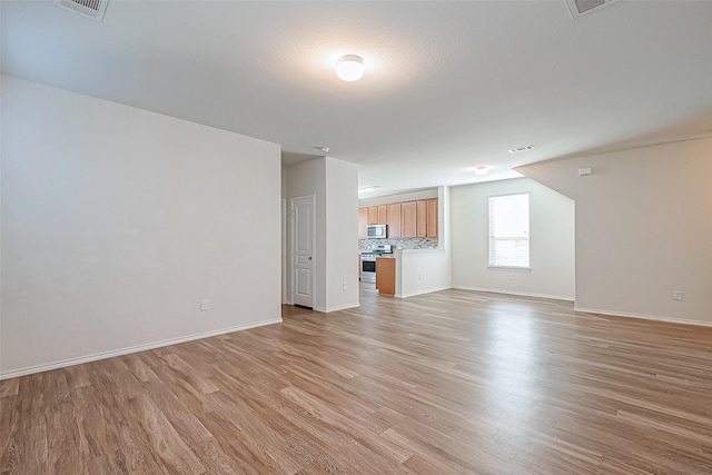 unfurnished living room with visible vents, baseboards, and light wood-style floors