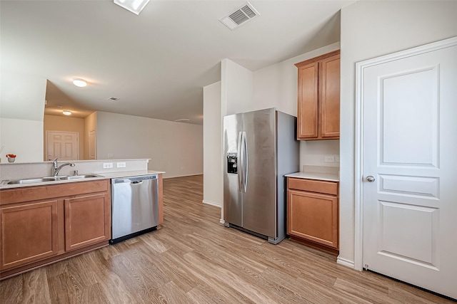 kitchen featuring a sink, brown cabinetry, visible vents, and stainless steel appliances