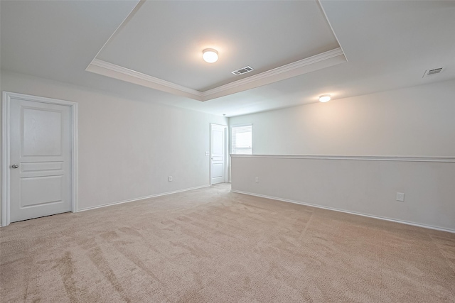 empty room with carpet, visible vents, baseboards, crown molding, and a raised ceiling