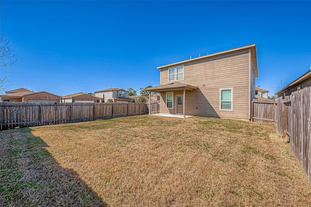 rear view of house featuring a lawn, a patio, and a fenced backyard