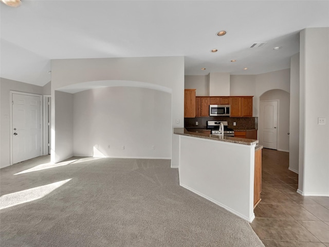 kitchen with lofted ceiling, light colored carpet, stainless steel appliances, and decorative backsplash