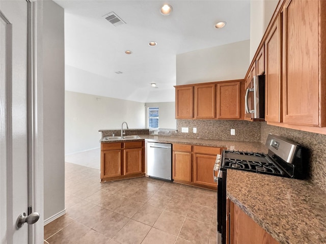 kitchen with sink, backsplash, kitchen peninsula, stainless steel appliances, and light stone countertops