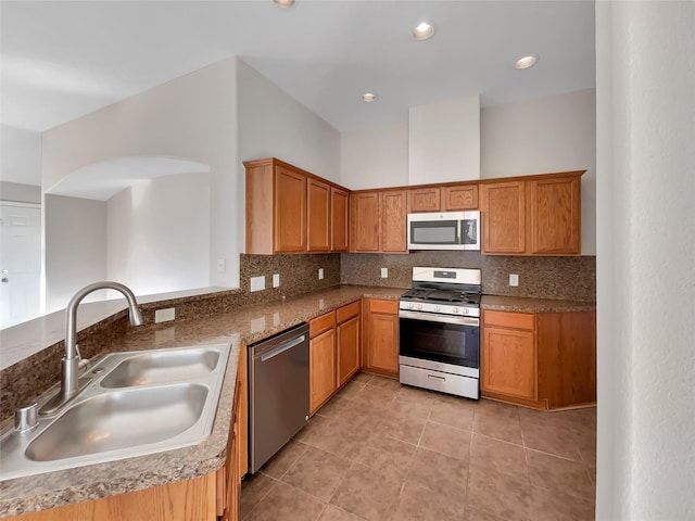 kitchen featuring light tile patterned flooring, appliances with stainless steel finishes, sink, decorative backsplash, and kitchen peninsula