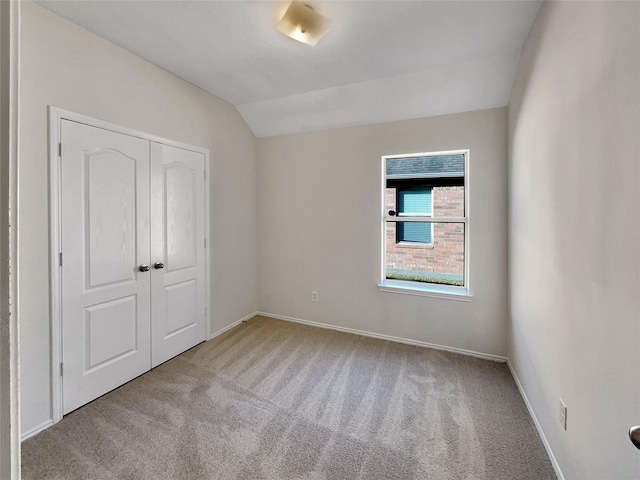 unfurnished bedroom with vaulted ceiling, light colored carpet, and a closet