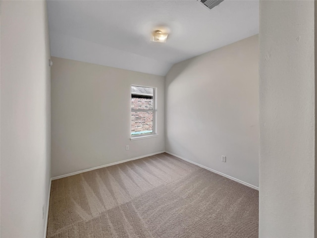 carpeted empty room featuring lofted ceiling