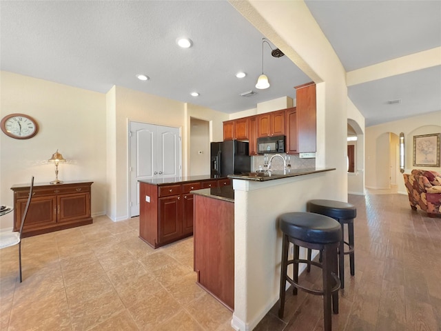 kitchen with pendant lighting, a kitchen breakfast bar, tasteful backsplash, black appliances, and kitchen peninsula