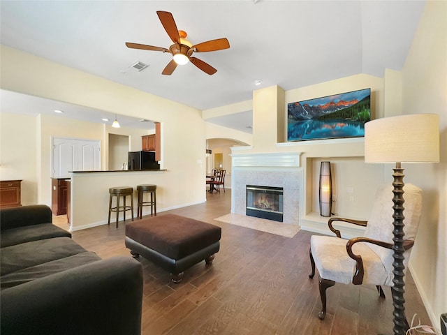 living room featuring vaulted ceiling, ceiling fan, a fireplace, and hardwood / wood-style floors