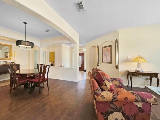 dining room featuring dark hardwood / wood-style flooring, a notable chandelier, washer / dryer, and ornamental molding