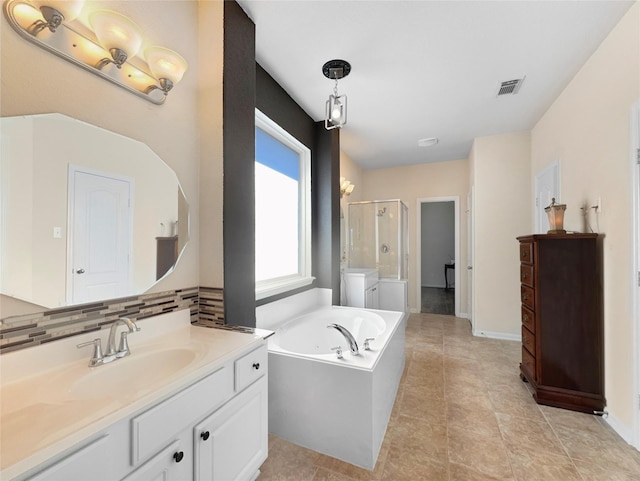 bathroom featuring vanity, shower with separate bathtub, washing machine and dryer, and backsplash