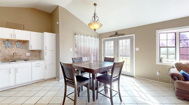 dining space with lofted ceiling, sink, light tile patterned floors, and french doors