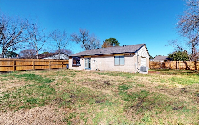 rear view of property featuring a lawn and central air condition unit