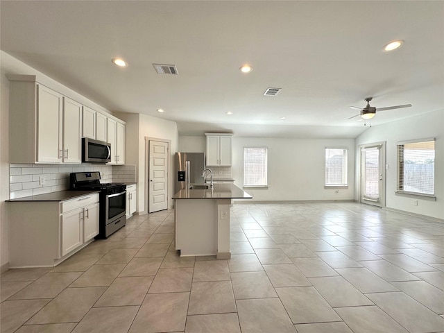 kitchen featuring a kitchen island with sink, sink, stainless steel appliances, and white cabinets