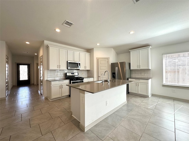 kitchen featuring sink, a kitchen island with sink, white cabinetry, backsplash, and stainless steel appliances