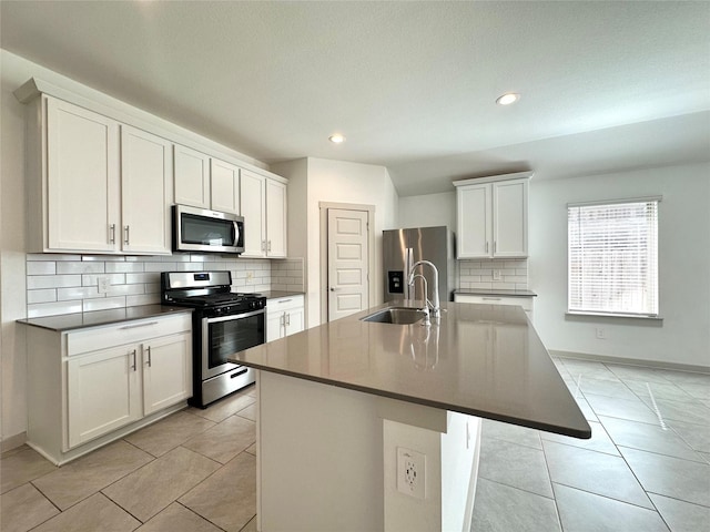 kitchen with white cabinetry, sink, stainless steel appliances, and an island with sink