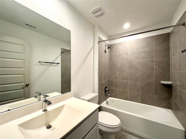 full bathroom featuring vanity, tiled shower / bath combo, and toilet