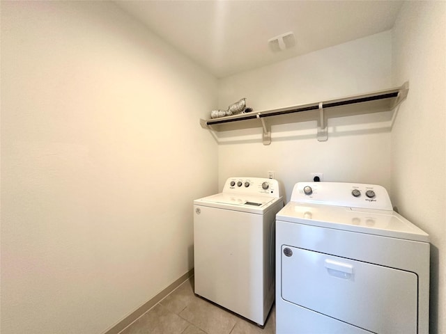 clothes washing area with washer and dryer and light tile patterned floors