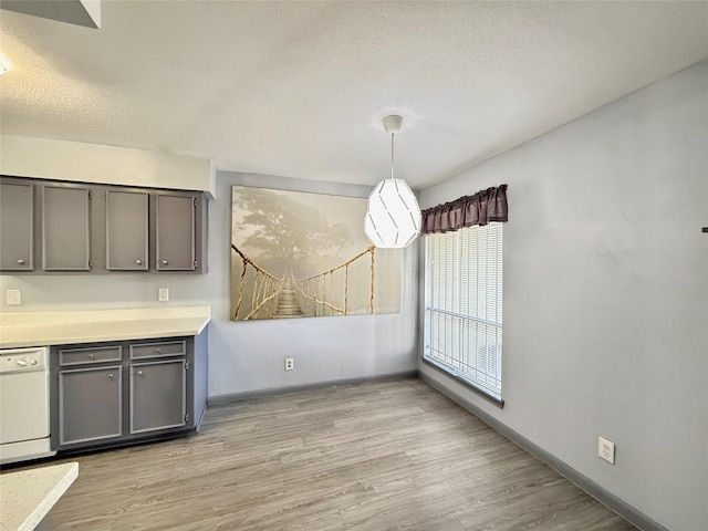 unfurnished dining area featuring a textured ceiling and light wood-type flooring