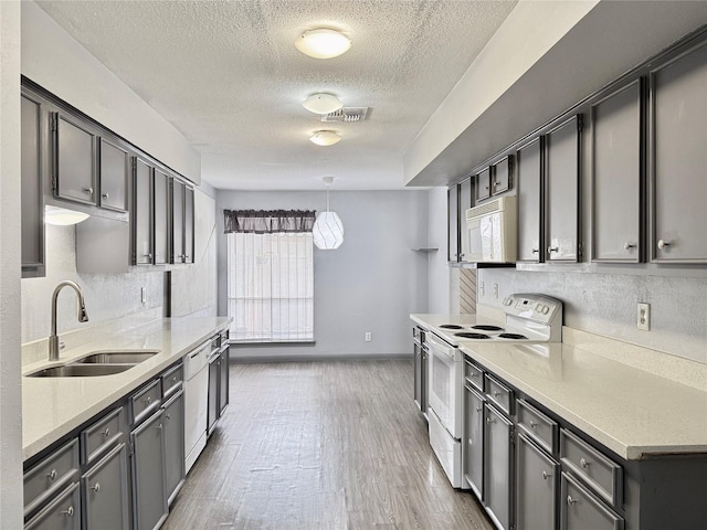 kitchen featuring sink, white appliances, decorative backsplash, dark hardwood / wood-style flooring, and decorative light fixtures