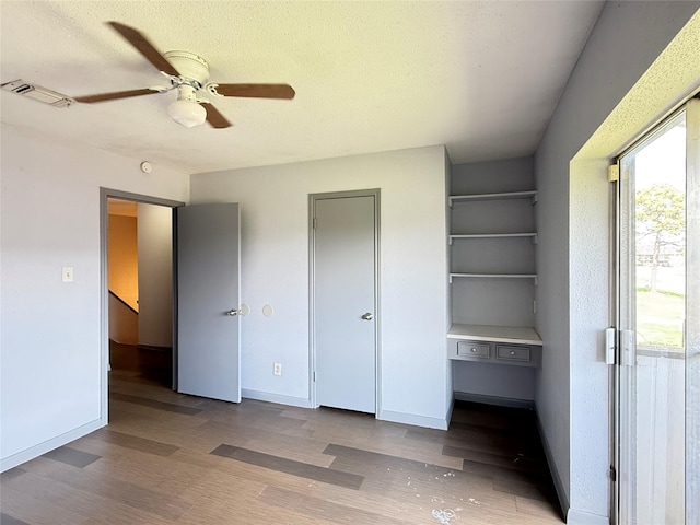 unfurnished bedroom featuring ceiling fan, wood-type flooring, and a textured ceiling