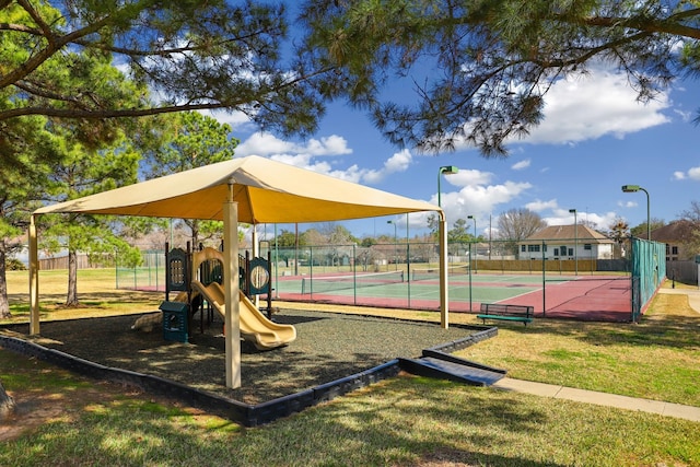 view of playground featuring tennis court and a lawn