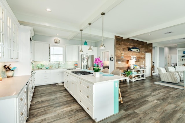 kitchen with a breakfast bar, a center island, appliances with stainless steel finishes, pendant lighting, and white cabinets