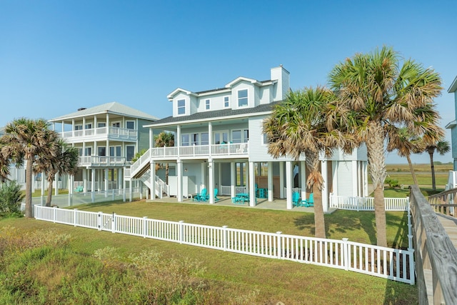 rear view of property featuring a balcony, a patio area, and a lawn