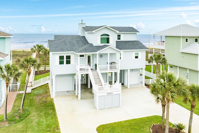 coastal inspired home featuring a garage, a front lawn, a water view, and a porch