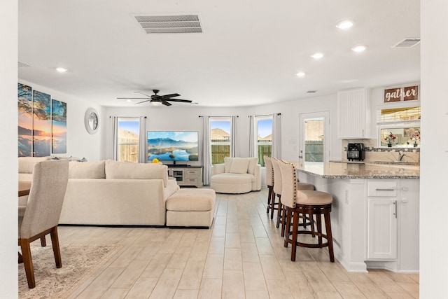 living room with sink, ceiling fan, and light hardwood / wood-style flooring