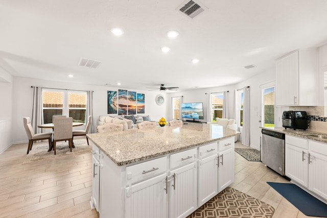 kitchen with dishwasher, white cabinets, a center island, light stone countertops, and light hardwood / wood-style flooring