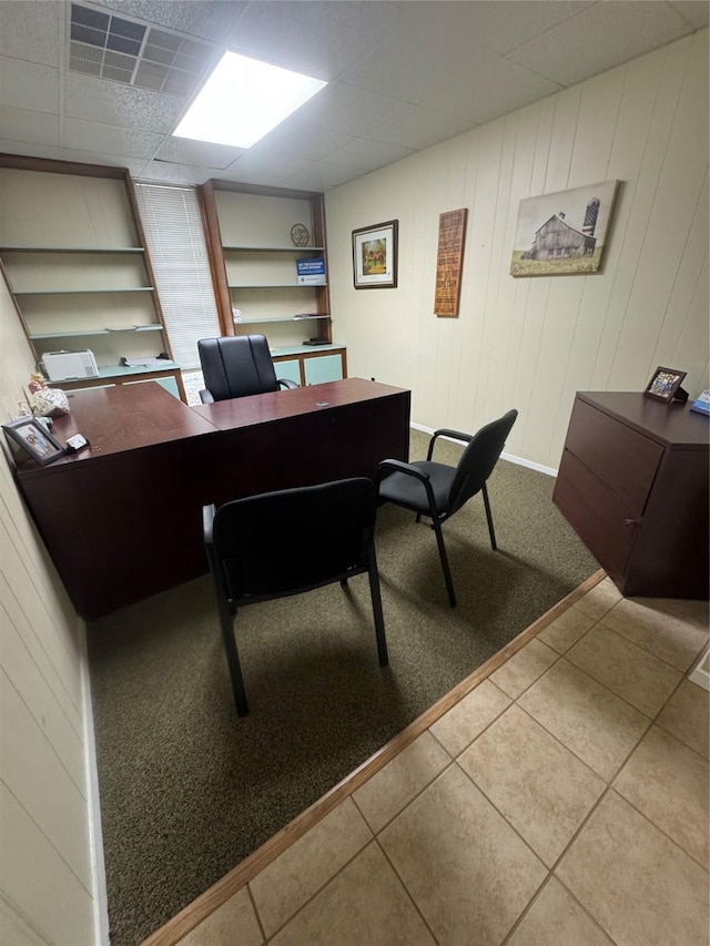 tiled office space with built in shelves and a paneled ceiling