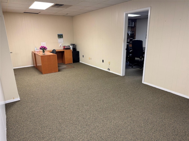 unfurnished office featuring a drop ceiling and dark carpet