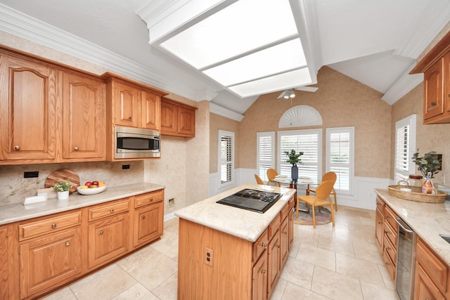 kitchen featuring light tile patterned floors, lofted ceiling with skylight, stainless steel appliances, light stone countertops, and a kitchen island