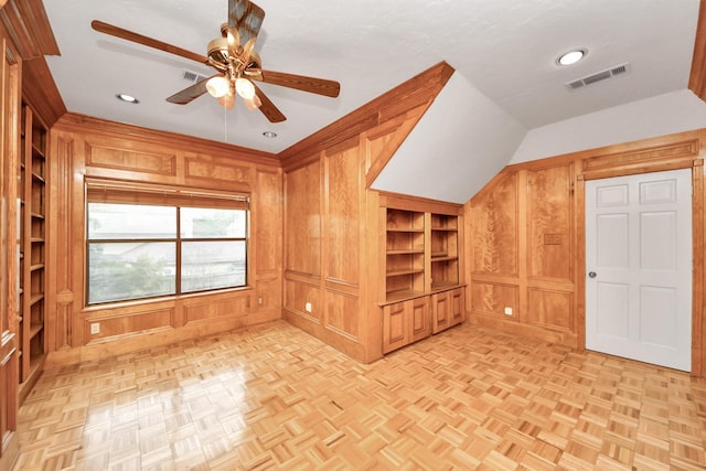 interior space featuring wood walls, vaulted ceiling, built in features, ceiling fan, and light parquet floors